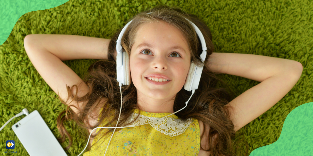 Mädchen liegt auf dem Teppich und hört Musik mit Kopfhörern