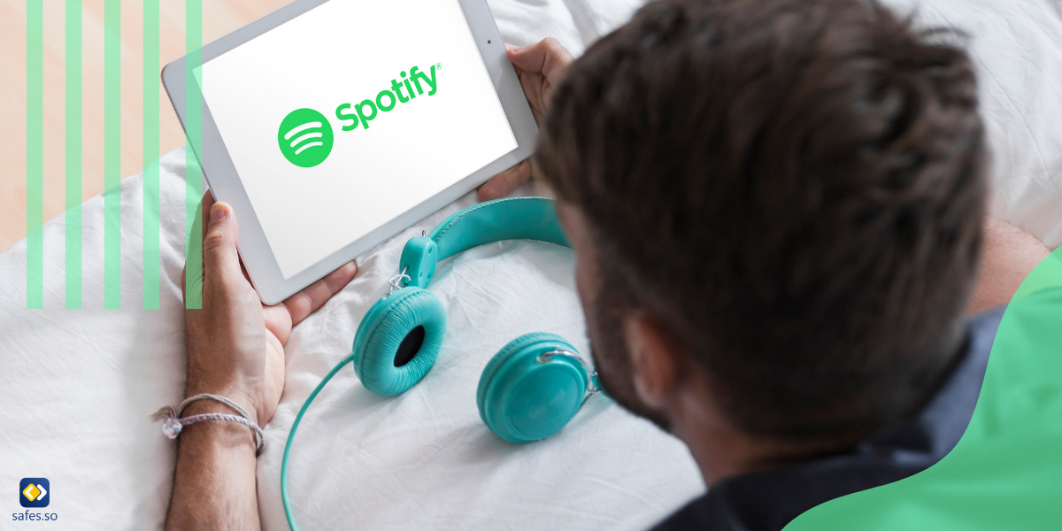 young man holding iPad that is displaying Spotify icon with headphones plugged in