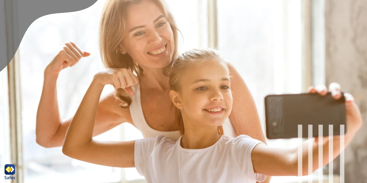 Mutter und Tochter machen ein Selfie, während sie ihre Muskeln spielen lassen und lächeln