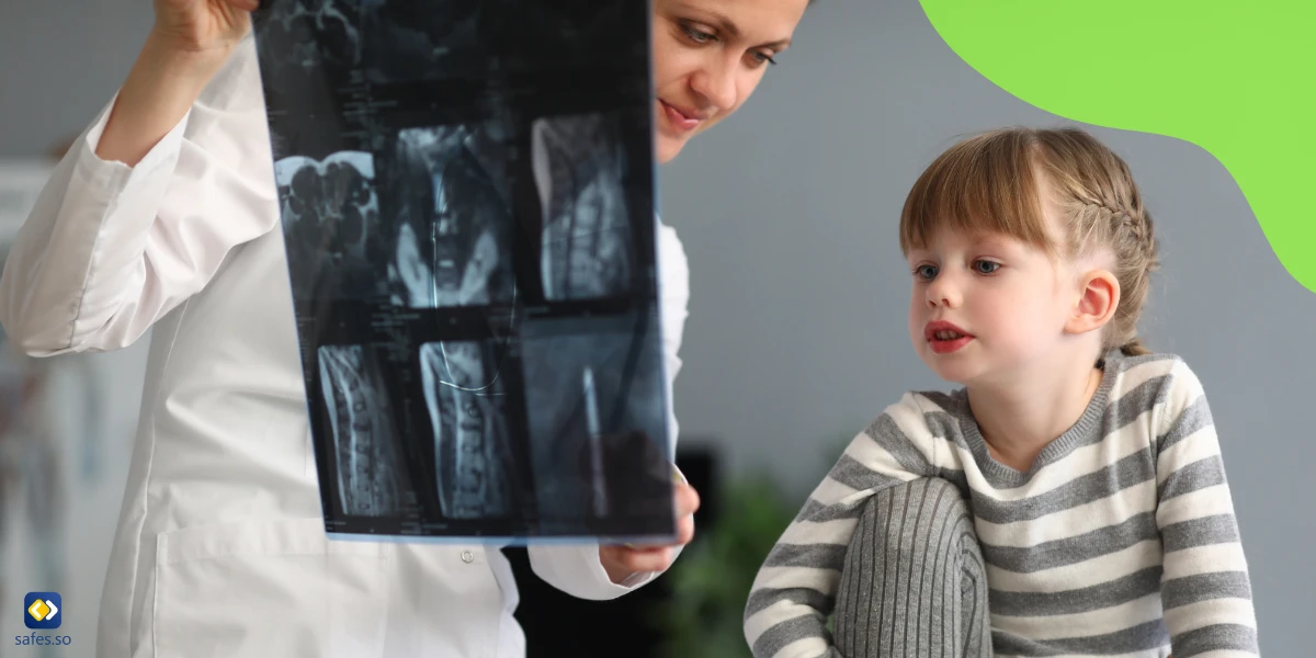 Doctor examining a kid’s spine showing her an x-ray of her spine