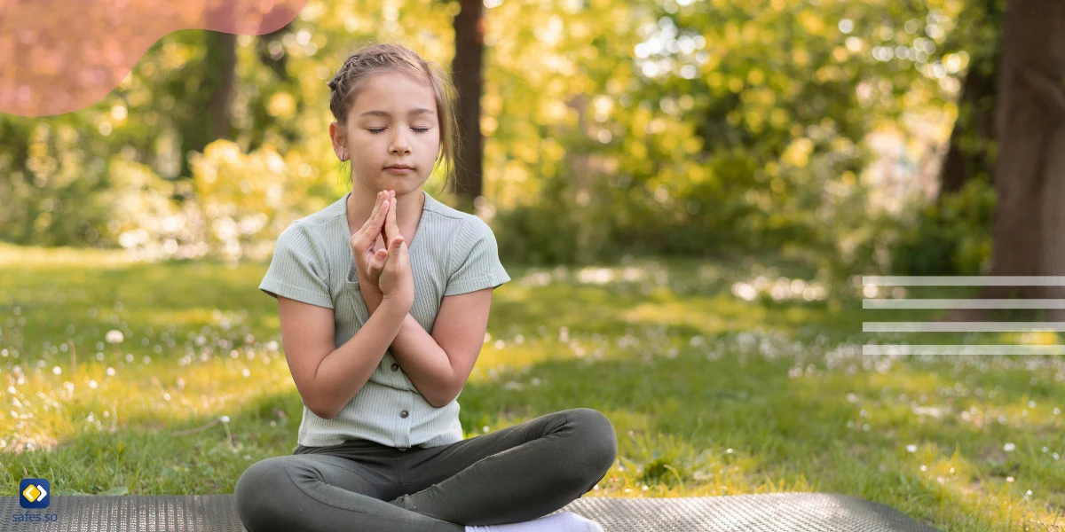 Kind meditiert auf dem Rasen