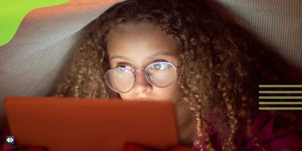 Mädchen mit Brille schaut unter einer Decke auf ein Tablet
