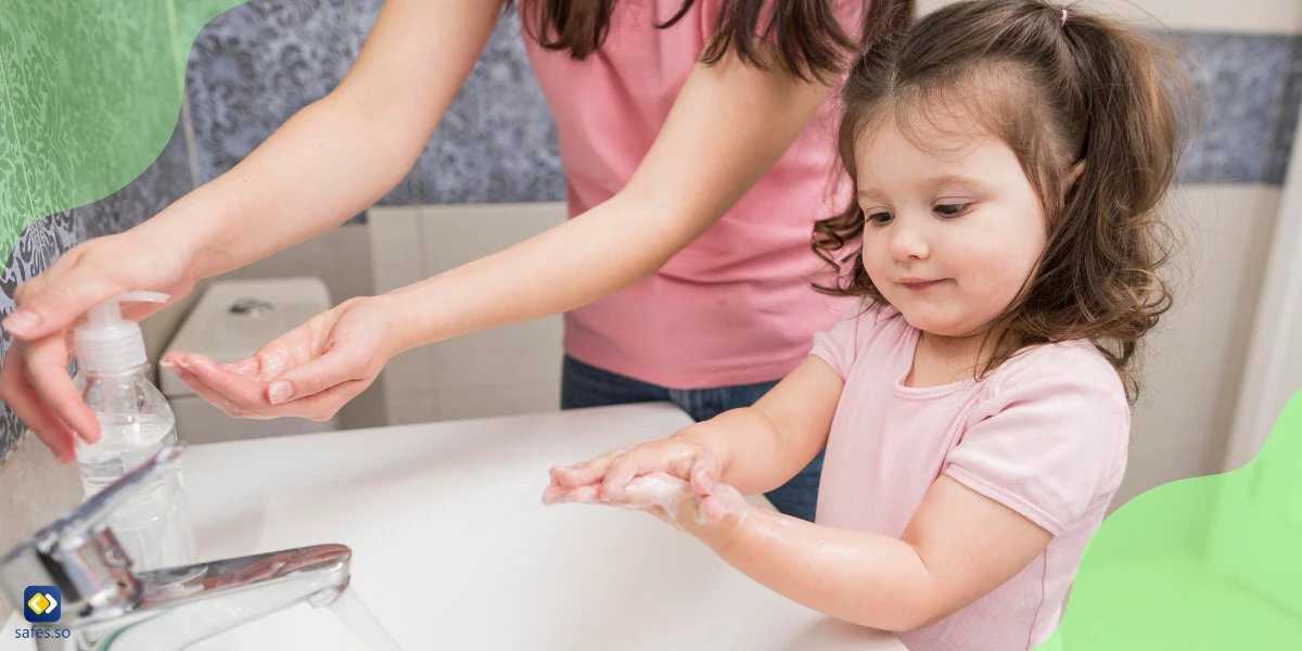 little girl washing her hands together with her mom