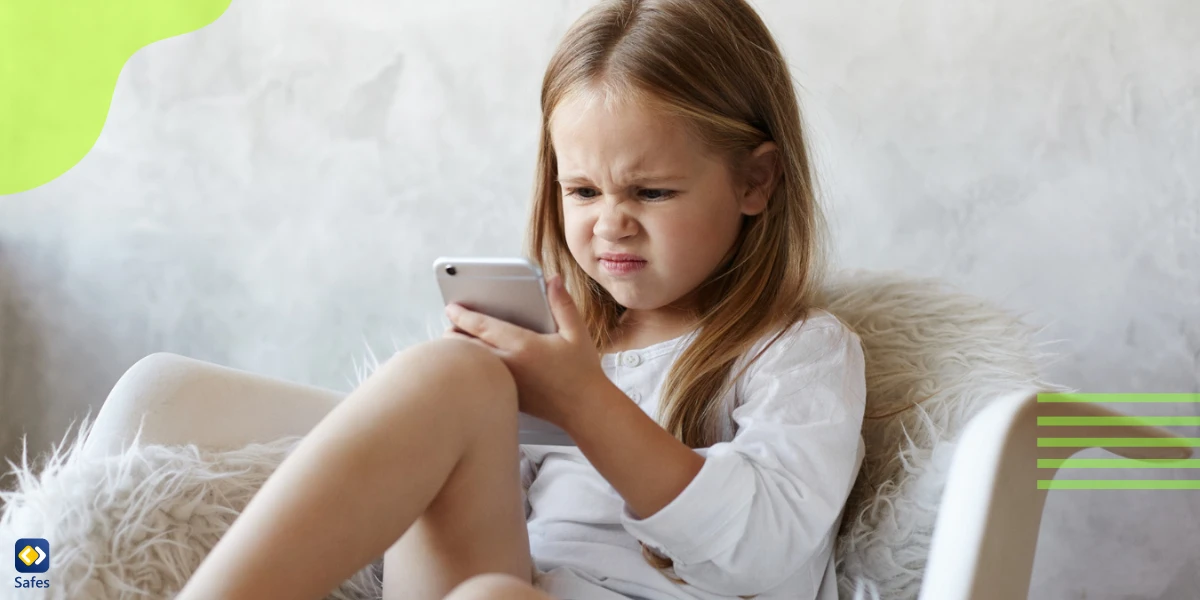 Little girl with a cross face in front of a phone
