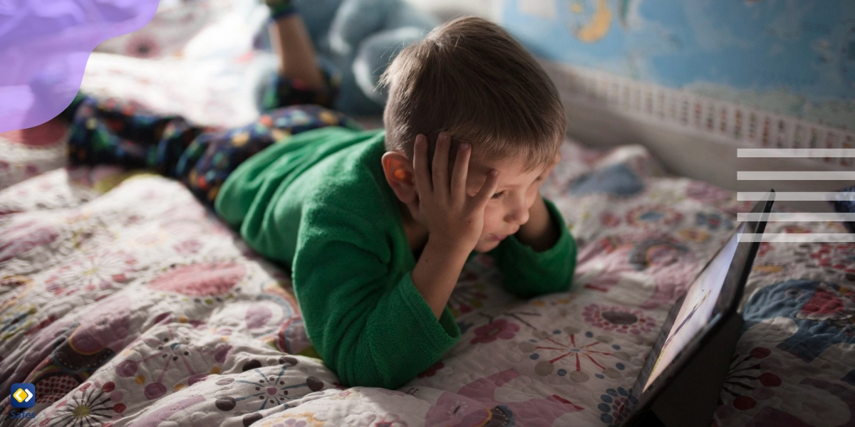 Boy holding his head and watching a screen on his bed