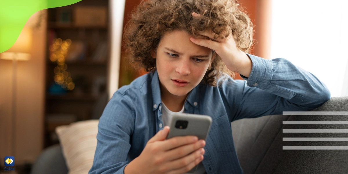 A teenage boy is looking at his cellphone angrily