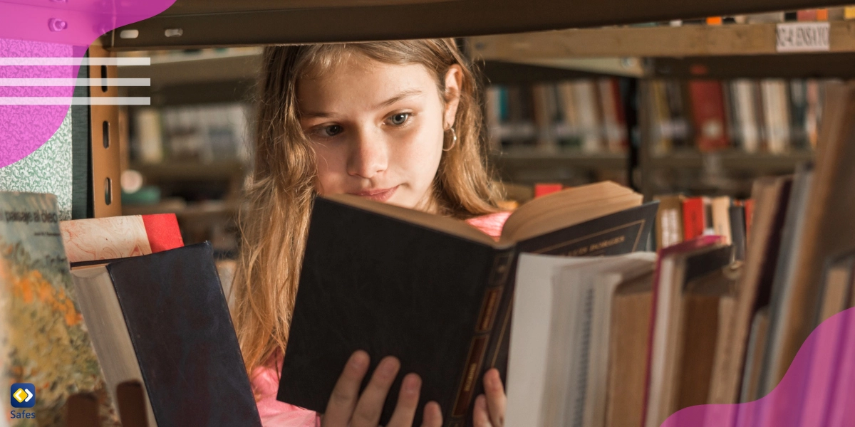 Ein kleines Mädchen liest ein Buch hinter einem Bücherregal