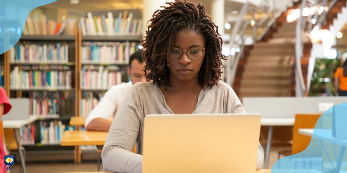 Eine junge Studentin in einer Bibliothek, die mit ihrem Laptop lernt