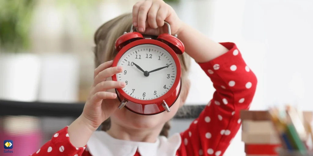 girl in red polka dot dress holding a red alarm clock in front of her face