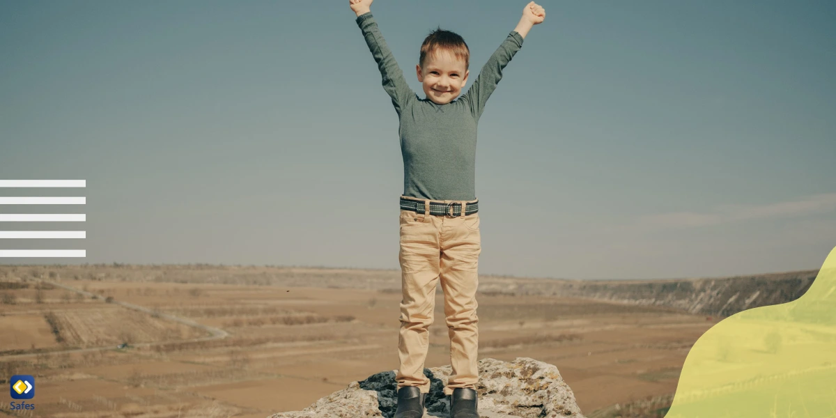 A boy feeling successful after climbing a rock.