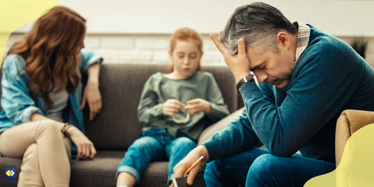 A visibly distressed father sitting on the couch, experiencing secondary trauma.