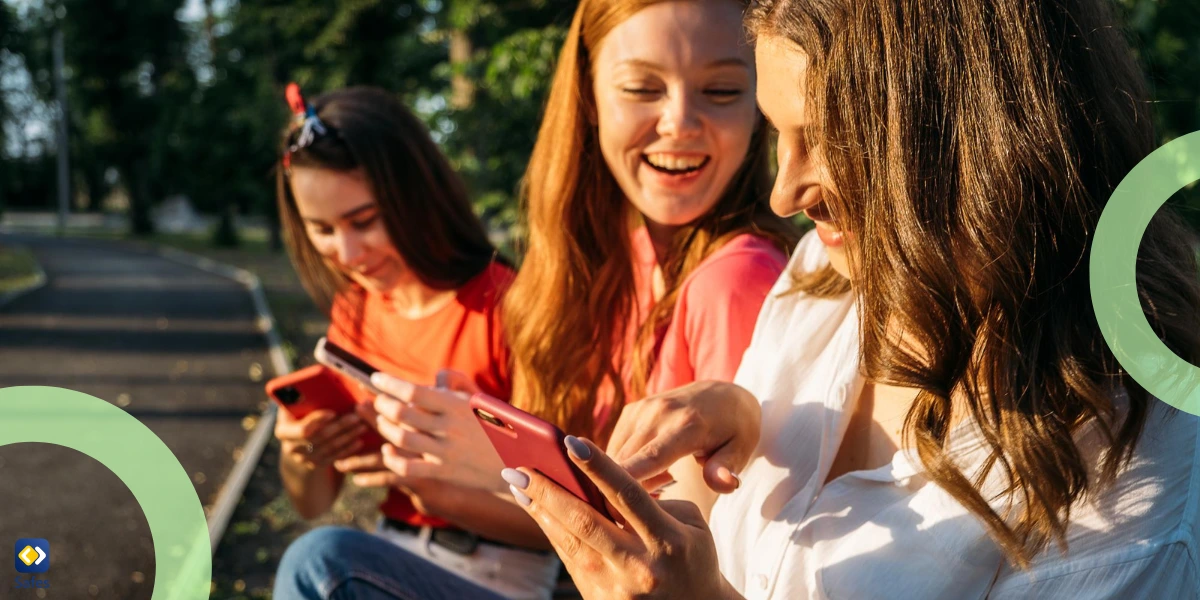 three happy girls watching their phones