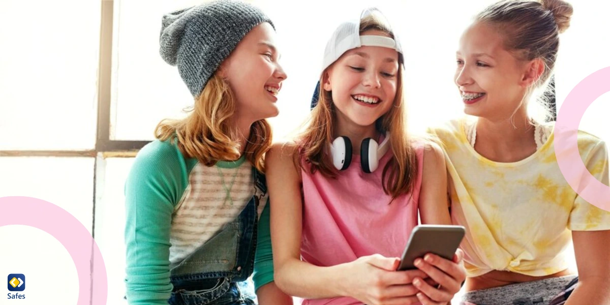 three teen girls laughing and showing each other something on a phone
