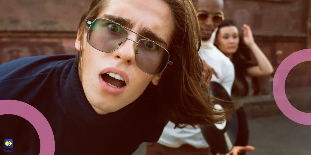 A young man in sunglasses leans toward the camera with a shocked or exaggerated expression, while two friends stand behind him, striking playful poses in an urban setting.