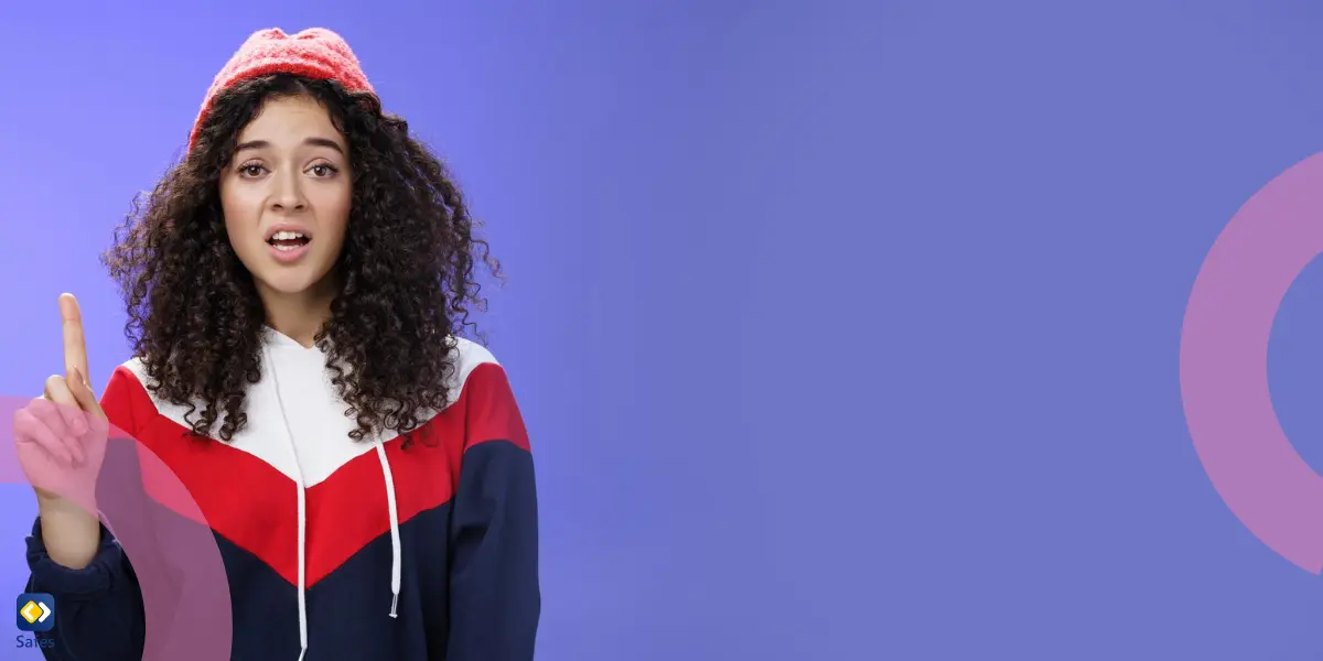 A teenage girl with curly hair wearing a red beanie and a sporty hoodie gestures with her index finger raised, looking surprised or disapproving against a purple background.