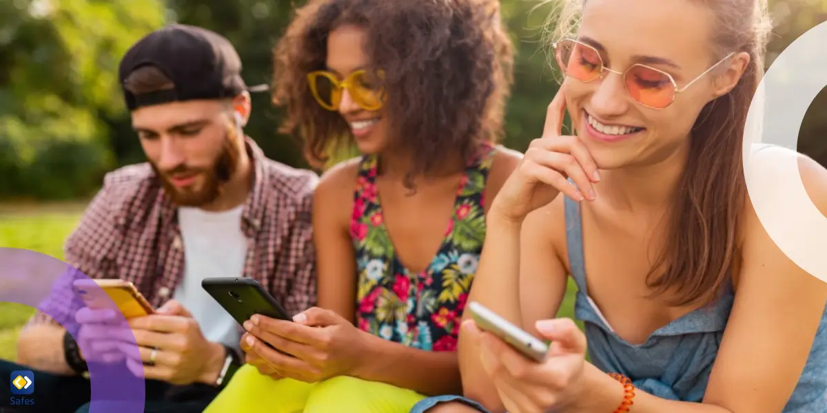 Three friends watching mobile smartphones and having fun sitting on a bench.
