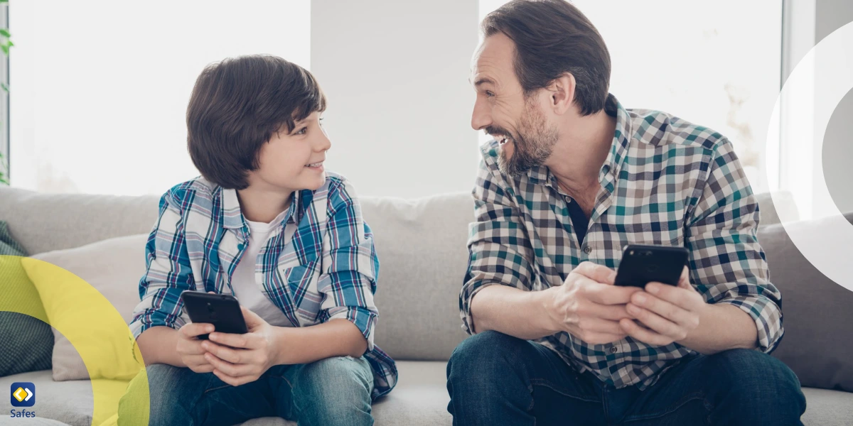 father and son smiling at each other while holding their phones