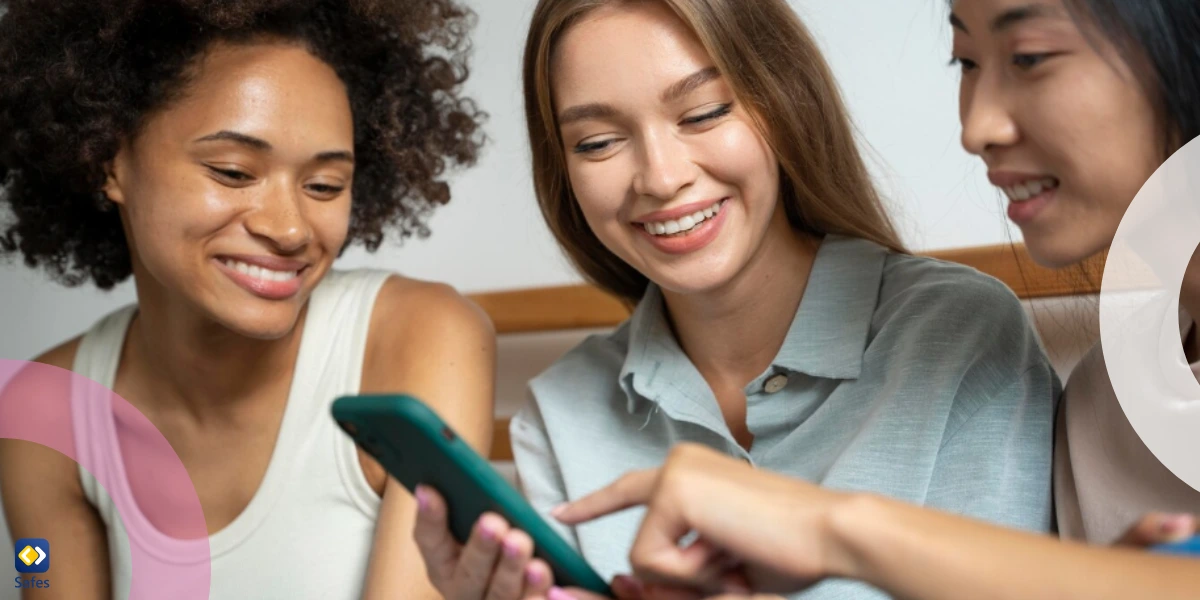 Three girls looking at a phone and smiling.