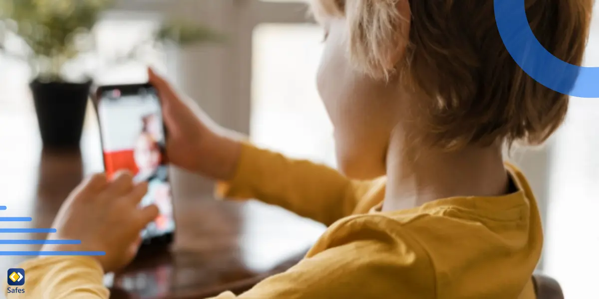 A kid having a video chat on his phone while sitting at a table.