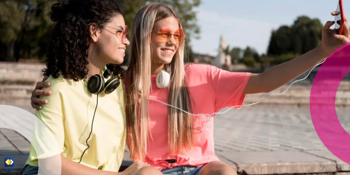 two girls taking selfies outside in the sun
